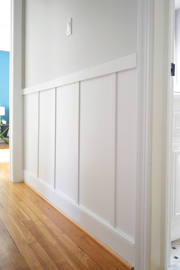 close up of board and batten trim detail in gray hallway with wood floors