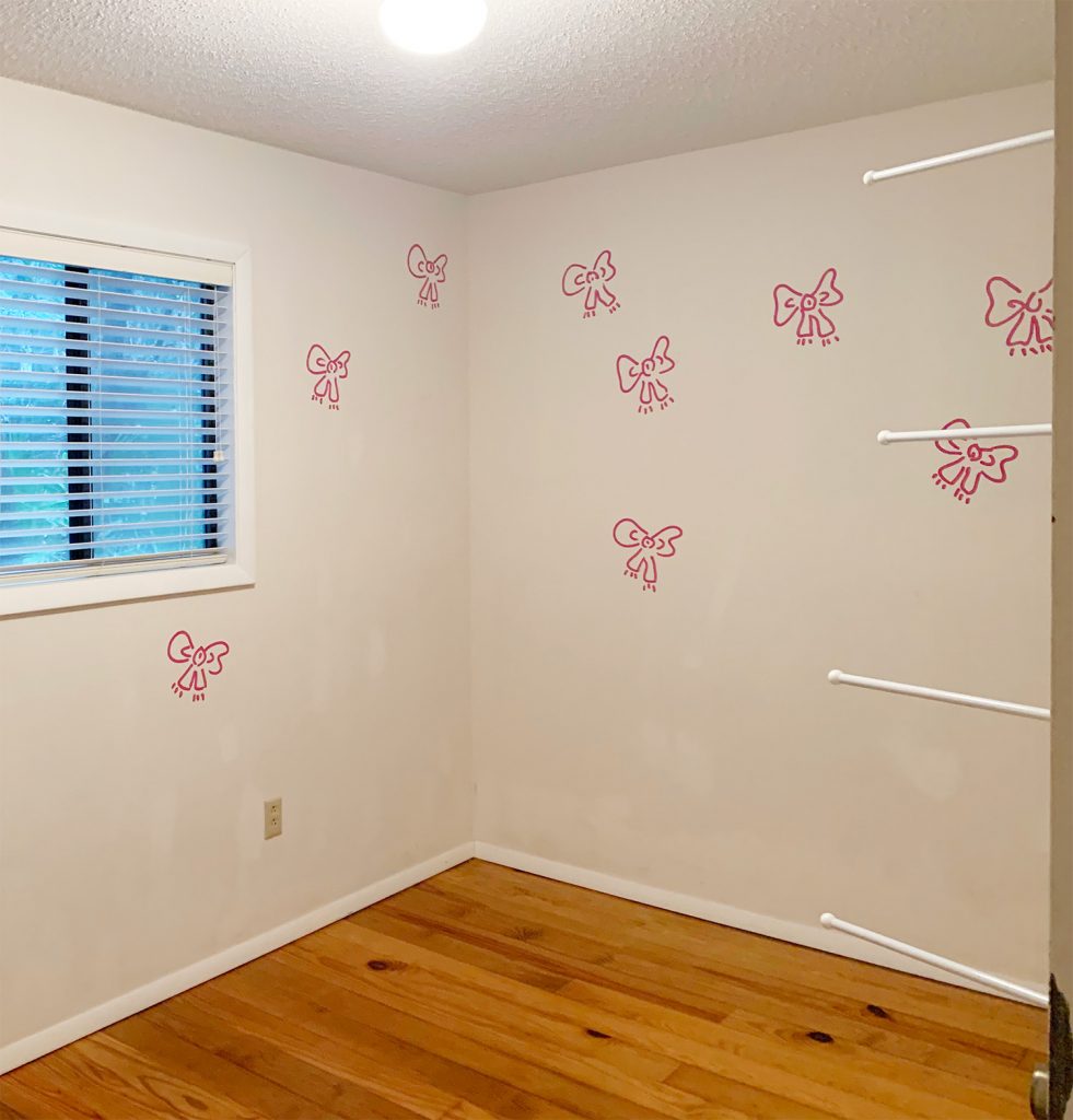 Before photo of boys room with white walls and pink bows painted randomly