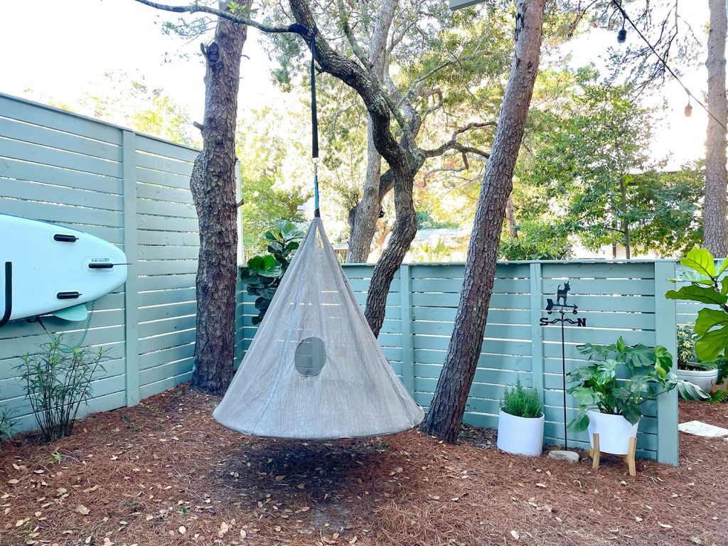 Side yard area with hanging tent swing near fence