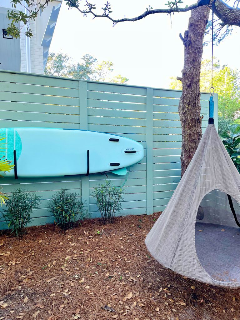 Side yard area with paddleboard stored on fence with hanging tent swing