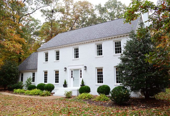 after photo of brick house painted moderne white in fall foliage