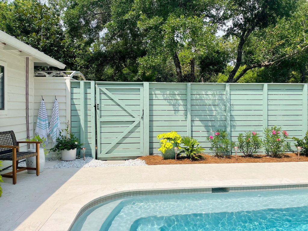 Pool fence with horizontal slats and gray green paint with planting bed in front
