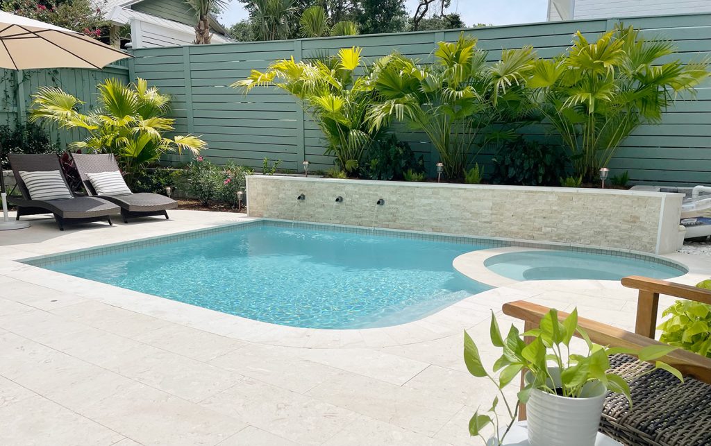 Widest view of full pool with round spa stone accent wall with fountains and tropical landscaping DiamondBrite Ivory plaster
