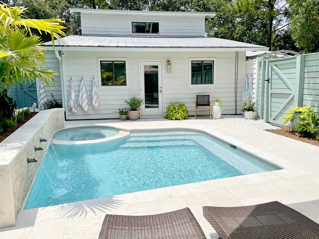 Small freeform pool with white house metal roof in background